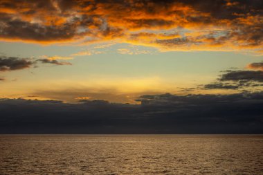 Güzel gökyüzündeki bulutlar gün batımında okyanusun üzerinde