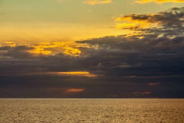 Güzel gökyüzündeki bulutlar gün batımında okyanusun üzerinde