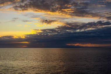 Güzel gökyüzündeki bulutlar gün batımında okyanusun üzerinde