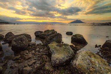 Alçak gelgitte bulutlu bir gün batımı. Makassar Plajı, Alor Kecil, Doğu Nusa Tenggara - Endonezya.