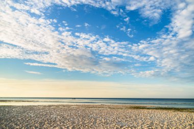 Beyaz kumlu deniz üzerinde yumuşak beyaz bulutların çekildiği mavi öğleden sonra gökyüzü manzarası. Pante Deere, Alor Adası, Doğu Nusa Tenggara - Endonezya