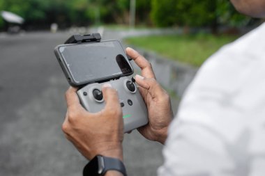 DJI Mavic Air 2 insansız hava aracının uzaktan kumandası cep telefonuna bağlı. Alor - Endonezya, 28 Nisan 2025