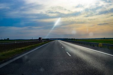Hareket halindeki bir aracın ön camından çekilen dinamik perspektif görüntüsü. Asfalt şerit mesafeye kadar uzanıyor.