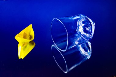 Neşeli sarı kağıttan bir yelkenli, temiz su dolu bir bardakta yüzer ve nostaljik bir çocukluk anısı yaratır. Güneş ışığı yansımaları cam yüzeyde dans eder...