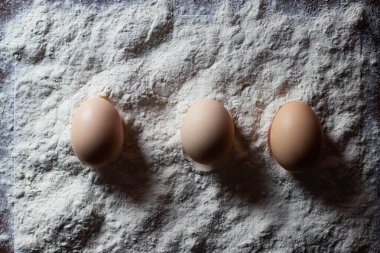 Yumuşak doğal ışıkla yıkanmış yıpranmış ahşap bir masanın üzerine yerleştirilmiş taze kahverengi yumurtaların basit ve zarif bir kompozisyonu. Bu organik yaşam, çiftlik tazeliği, sağlıklı beslenme ve ev yapımı yemek temaları çağrıştırıyor. Yemek blogları için mükemmel, organik