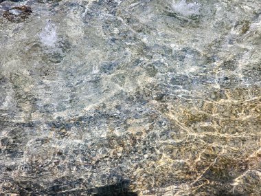 Yumuşak dalgalanmalar ve yansımalarla sakin bir su yüzeyine yakın çekim. Tasarım, doğa temaları, rahatlama görselleri ve çevresel kavramlar için doğal bir arka plan veya doku olarak idealdir..