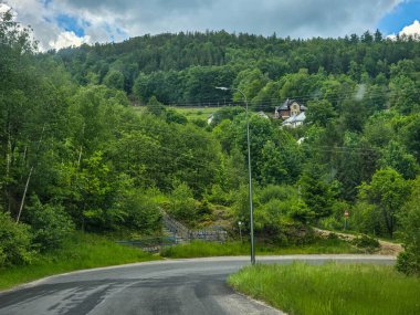 Yüksek tepelerden geçen dolambaçlı bir yolu olan çarpıcı bir dağ manzarası. Seyahat reklamları, ilham verici projeler ve macera markaları için mükemmel.