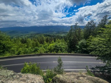 Yüksek tepelerden geçen dolambaçlı bir yolu olan çarpıcı bir dağ manzarası. Seyahat reklamları, ilham verici projeler ve macera markaları için mükemmel.
