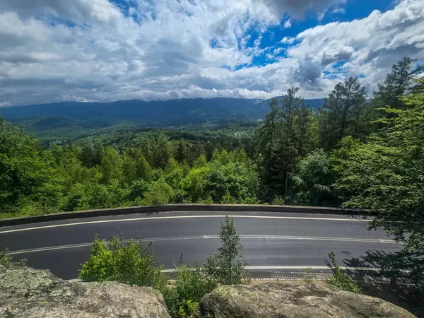Yüksek tepelerden geçen dolambaçlı bir yolu olan çarpıcı bir dağ manzarası. Seyahat reklamları, ilham verici projeler ve macera markaları için mükemmel.