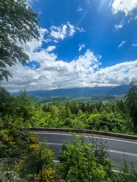 Yüksek tepelerden geçen dolambaçlı bir yolu olan çarpıcı bir dağ manzarası. Seyahat reklamları, ilham verici projeler ve macera markaları için mükemmel.