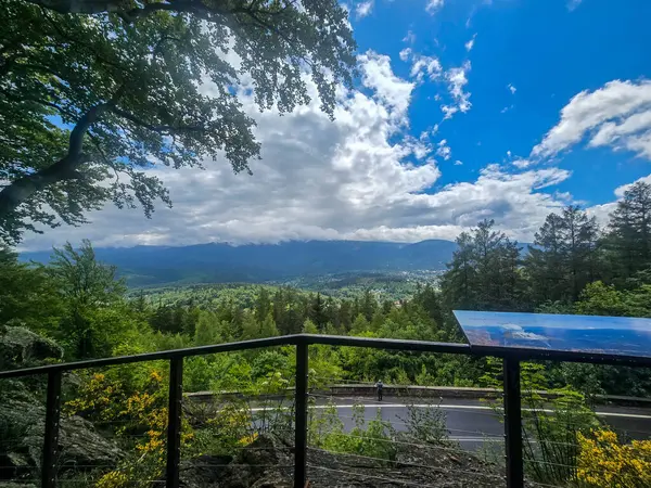 Yüksek tepelerden geçen dolambaçlı bir yolu olan çarpıcı bir dağ manzarası. Seyahat reklamları, ilham verici projeler ve macera markaları için mükemmel.