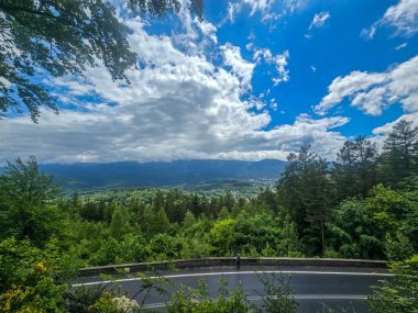 Yüksek tepelerden geçen dolambaçlı bir yolu olan çarpıcı bir dağ manzarası. Seyahat reklamları, ilham verici projeler ve macera markaları için mükemmel.