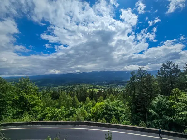 Yüksek tepelerden geçen dolambaçlı bir yolu olan çarpıcı bir dağ manzarası. Seyahat reklamları, ilham verici projeler ve macera markaları için mükemmel.
