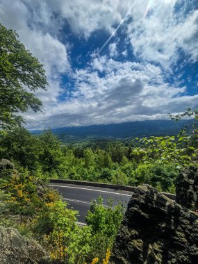 Yüksek tepelerden geçen dolambaçlı bir yolu olan çarpıcı bir dağ manzarası. Seyahat reklamları, ilham verici projeler ve macera markaları için mükemmel.