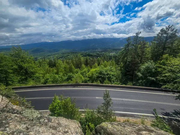 Yüksek tepelerden geçen dolambaçlı bir yolu olan çarpıcı bir dağ manzarası. Seyahat reklamları, ilham verici projeler ve macera markaları için mükemmel.