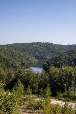 Bu nefes kesici manzara fotoğrafı el değmemiş bir alp gölü yakalar etrafındaki yeşil ormanı ve yüksek dağ zirvelerini mükemmel bir şekilde yansıtır. Kristal berrak sular, bu el değmemiş güzelliğin iki katını oluşturan aynaya benzer bir yüzey yaratır.