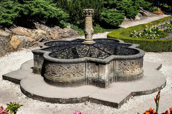 Bu yüksek çözünürlüklü fotoğraf, genellikle dilek çeşmesi olarak bilinen dekoratif bir para çeşmesini yakalar, ziyaretçilerin dilek tutarken bozuk para attığı yer. Görüntü, suyun ışıldayan yüzeyini vurgular. Düşerken oluşan hafif dalgalanmaları.