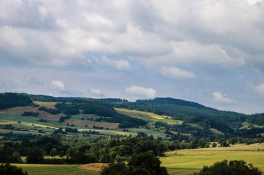 Bu büyüleyici doğa manzarası bir huzur, durgunluk ve açık alan hissi veriyor. Çerçevede, açık ve geniş mavi gökyüzünün altındaki yoğun yeşil bir ormana dönüşen sonsuz alanlar yer alıyor. Doğal elementler arasındaki mükemmel denge...