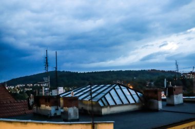 Bu fotoğraf, canlı bir şehir manzarasına bakan etkileyici bir çatı manzarası yakalıyor ve şehir mimarisinin karmaşık güzelliğini yukarıdan gösteriyor. Yüksek bir açıdan bakıldığında, görüntü çatıların, konut binalarının, ofis binalarının karışımını ortaya çıkarıyor.