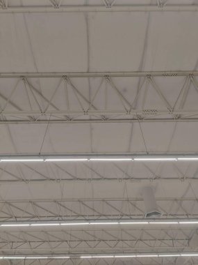 Görünür metal yapısı ve floresan ışıklandırması olan bir deponun iç manzarası. Uzay, ürünleri depolamak için ideal bir yer ve işlevsellik hissi taşır..