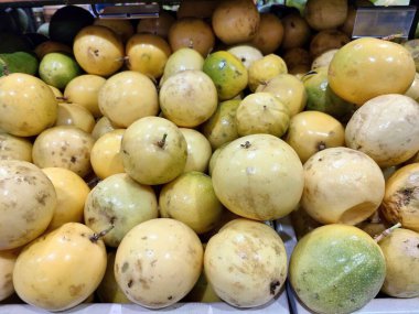 Çoğunluğu sarı ve yeşil olan egzotik meyve bolluğu bir pazarda istiflenmiştir. Değişik deri ve dokuları canlı, doğal bir atmosfer yaratır. Tazelik ve lezzet uyandırır..