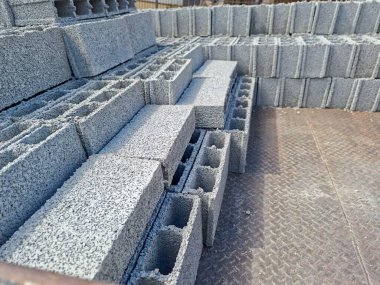 Gri beton bloklardan oluşan düzenli bir resim. Malzemenin sert ve sağlam dokusunu gösteriyor. Doğal ışık, bir inşaat ortamında blokların sertliğini ve tekdüzeliğini vurguluyor. İnşaat mühendisliği ve kemer için ideal.