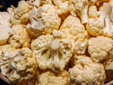 Büyük miktarda taze karnabahar, beyaz desenli çiçeklerini sergiliyor, zengin ve sulu bir yığın halinde düzenleniyor. Görüntü, bu sağlıklı sebzenin doğal güzelliğini ve ham dokusunu vurguluyor. Tazelik hissi uyandırıyor.