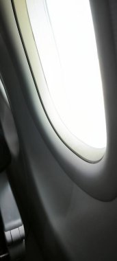 Açık bir günde bir uçak penceresinden parlak bir manzara, mavi gökyüzünü ve yumuşak bulutları gösterir, seyahat, havacılık ve ulaşımla ilgili konular için mükemmeldir.