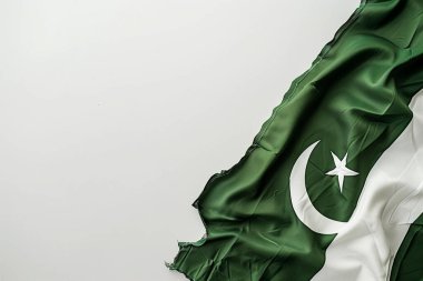 Beyaz hilal şeklinde bir Pakistan bayrağı ve yeşil ipek arkaplanda bir yıldız var. Işık kumaştan yansıyor, solda beyaz bir zemin var..