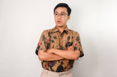 Yüzünde batik ve gözlük olan Asyalı bir adam göğsünde çapraz kollar hareketi yapıyor.