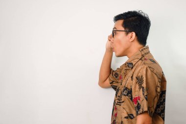 Batik ve gözlük takan, jest yapan ve elinde gözlük tutan Asyalı bir adam.