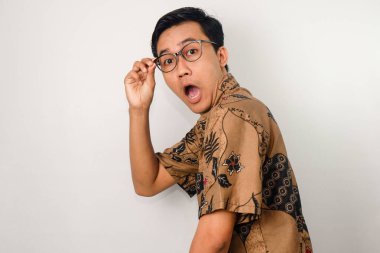 Batik takan, kameraya dönük gözlüklü, elinde gözlük olan Asyalı bir adam.