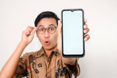 Akıllı telefona odaklanmış gözlüklü Asyalı adamın tuttuğu beyaz ekranlı akıllı telefon. Yüzünde bulanıklık, elinde gözlük.
