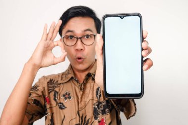 Akıllı telefonlara odaklanmış gözlüklü Asyalı adamın tuttuğu beyaz ekranlı akıllı telefon. Yüzü bulanık, elleri güzel bir sembol.