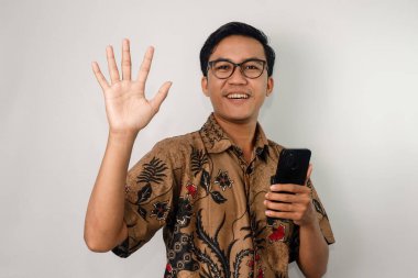 Kameraya el sallayan akıllı telefon tutan gözlüklü bir Asyalı.