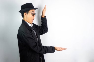 Mafya gibi giyinmiş, gözlüklü ve şapkalı Asyalı bir adam.