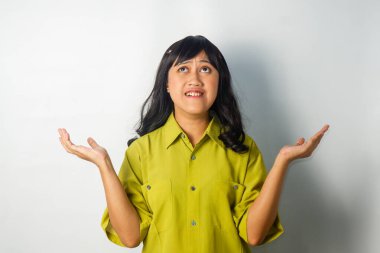 Yeşil tişört giyen, panikleyen ve ellerini kaldıran kendine güvenen Asyalı bir kadın.