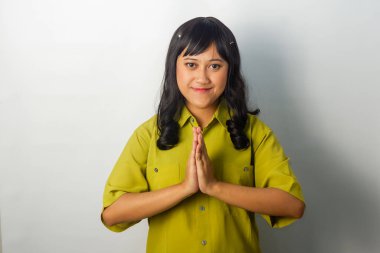 Yeşil tişört giyen kendine güvenen Asyalı bir kadın, sakin bir ifadeyle, hoş bir jest yapıyor.