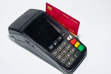 Kırmızı kredi kartının resmi EDC makinesine sıkışmış, beyaz arka planda izole edilmiş.