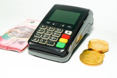 Bitcoin sikkeleri ve Endonezya Rupiah banknotları ile bir ödeme terminali, kripto para ve nakit entegrasyonunu gösteren modern finansal işlemler
