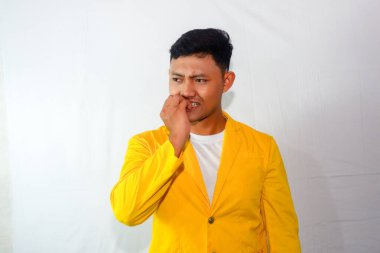 Sarı takım elbiseli genç Asyalı korkudan tırnaklarını yiyor.