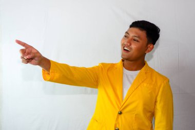 Genç Endonezyalı takım elbiseli adam gülümseyen tarafı işaret ediyor.