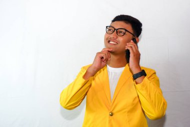Sarı ceketli ve gözlüklü genç Endonezyalı telefonda konuşuyor.
