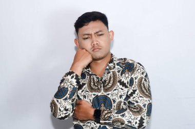 Batik giyen genç Endonezyalı adam düşünme hareketi yapıyor.