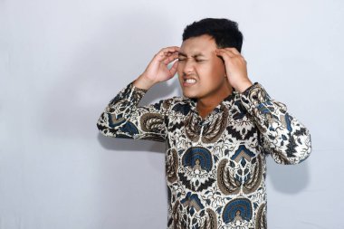 Endonezyalı genç adam baş ağrısı yüzünden batik takıyor.