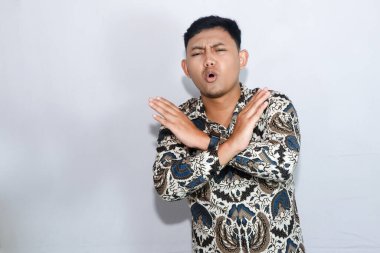 Batik giyen genç Endonezyalı adam dur işareti yapıyor.