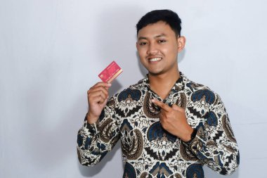 Genç Endonezyalı gülen yüzlü adam kredi kartını gösteriyor ve kredi kartını işaret ediyor.