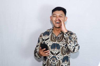 Dost canlısı Endonezyalı genç adam elinde cep telefonuyla bağırıyor.