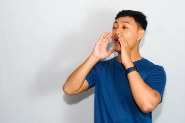 Mavi tişörtlü Asyalı adam bağırıyor ya da çağırıyor