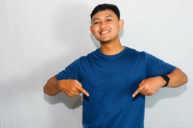 Asyalı adam mavi tişörtünü gösterip gülüyor.